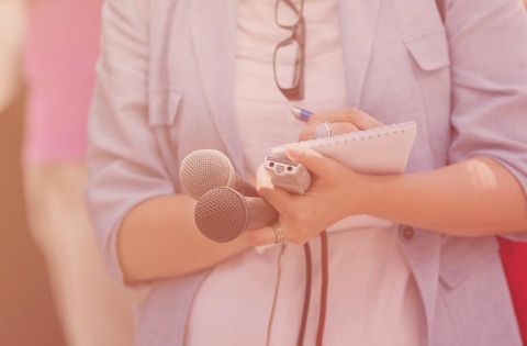 Hände einer Journalistin mit Mikrofonen und Notizblock