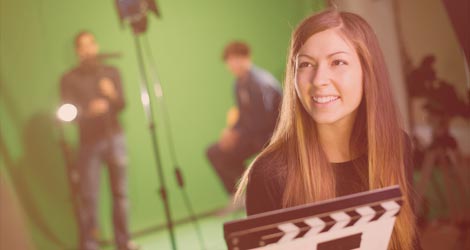 Studentin mit Filmklappe vor Green Screen