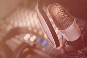 Bildausschnitt zeigt Mikrofon, Mischpult und Kopfhörer in einem Tonstudio