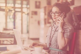 PR-Beraterin sitzt am Schreibtisch und telefoniert